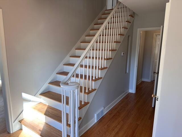 staircase featuring visible vents, baseboards, and wood finished floors