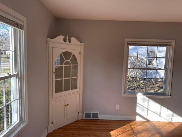 unfurnished dining area with visible vents, baseboards, and wood finished floors