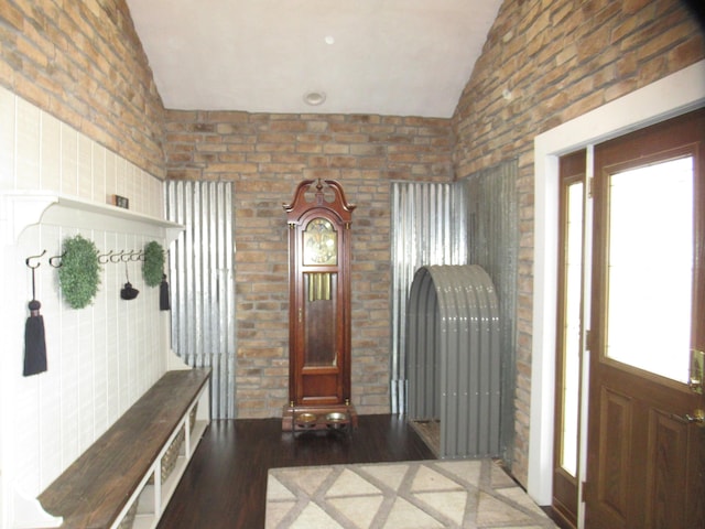 foyer featuring hardwood / wood-style flooring, brick wall, and lofted ceiling