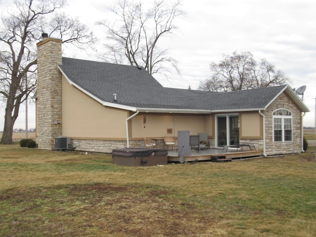 rear view of house featuring a wooden deck, central AC, a lawn, and a hot tub