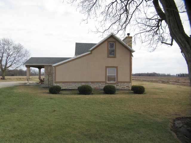 view of side of home with a yard and a rural view