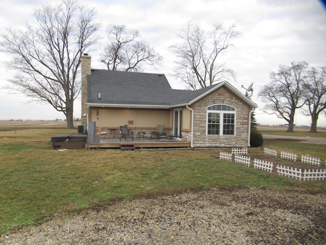 rear view of property featuring cooling unit, a yard, a hot tub, and a deck