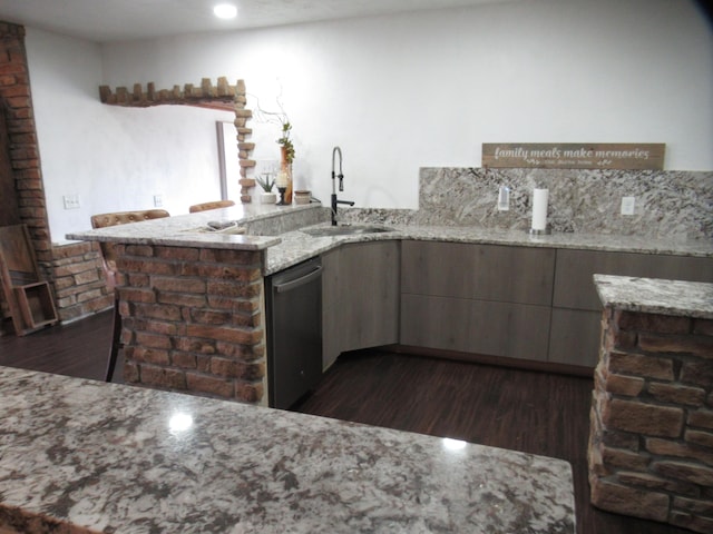 kitchen featuring stainless steel dishwasher, dark hardwood / wood-style floors, light stone countertops, and sink