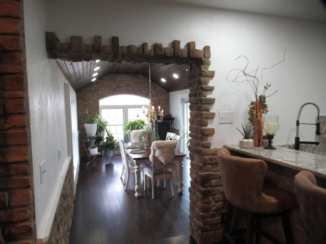 dining space featuring an inviting chandelier, sink, dark hardwood / wood-style flooring, and vaulted ceiling