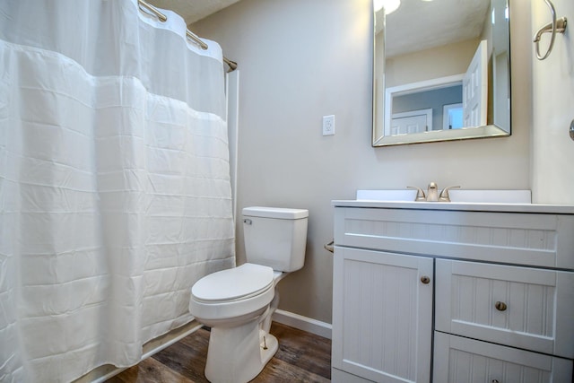 bathroom with toilet, curtained shower, wood finished floors, baseboards, and vanity