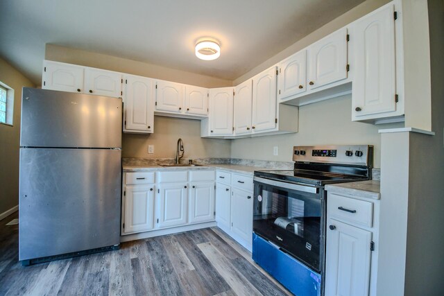 kitchen with light countertops, light wood-style flooring, appliances with stainless steel finishes, white cabinetry, and a sink