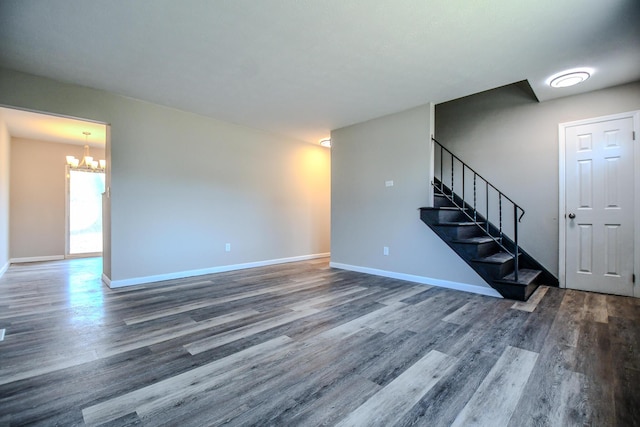 unfurnished living room with stairway, baseboards, an inviting chandelier, and wood finished floors