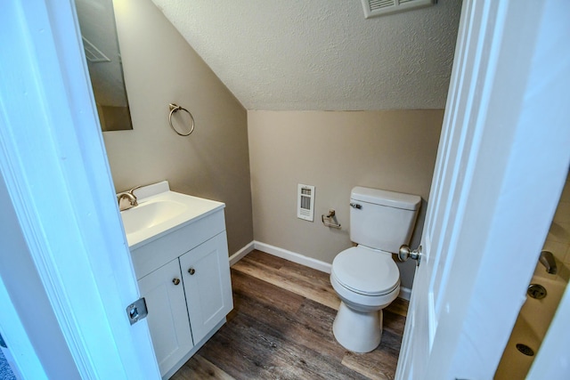 bathroom with visible vents, lofted ceiling, wood finished floors, heating unit, and a textured ceiling