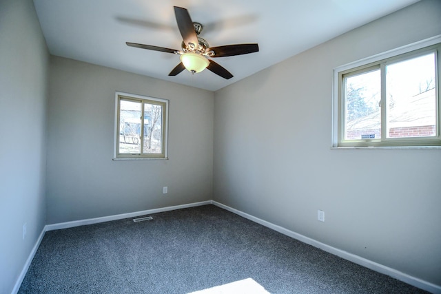 spare room with visible vents, baseboards, ceiling fan, and dark carpet