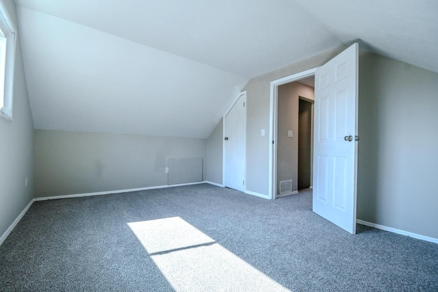 additional living space with visible vents, lofted ceiling, baseboards, and carpet flooring