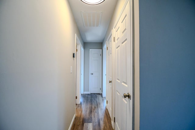 hall with dark wood-type flooring, baseboards, and visible vents