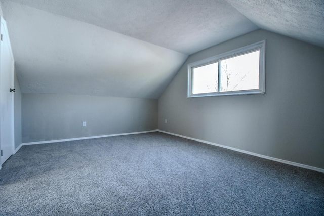 additional living space featuring lofted ceiling, baseboards, a textured ceiling, and carpet floors