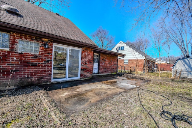 rear view of property with a patio area, brick siding, roof with shingles, and fence