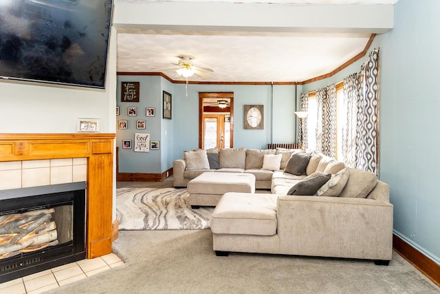 living room featuring baseboards, ornamental molding, a fireplace, and a ceiling fan