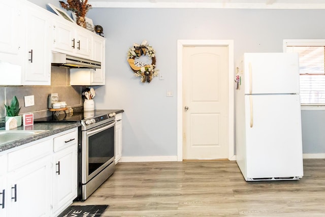 kitchen with light wood-type flooring, under cabinet range hood, stainless steel electric stove, dark countertops, and freestanding refrigerator