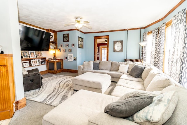 carpeted living room with baseboards, crown molding, and a ceiling fan