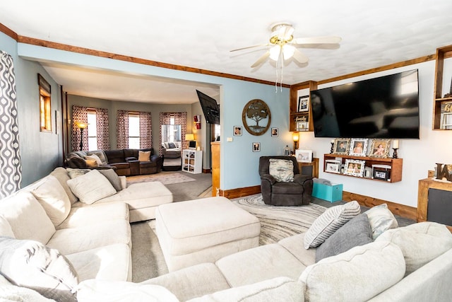 living room featuring baseboards, ceiling fan, and ornamental molding