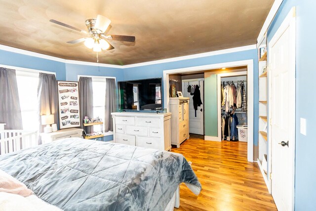 bedroom with ornamental molding, light wood-style flooring, and ceiling fan