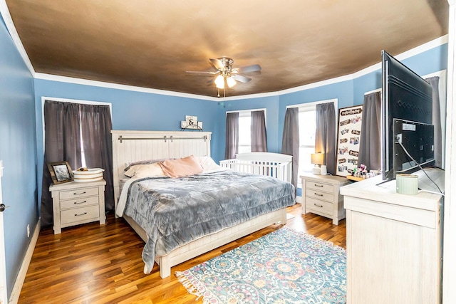 bedroom with baseboards, ornamental molding, wood finished floors, and ceiling fan