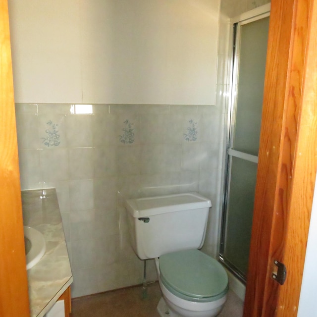 bathroom with vanity, a shower stall, toilet, and tile walls