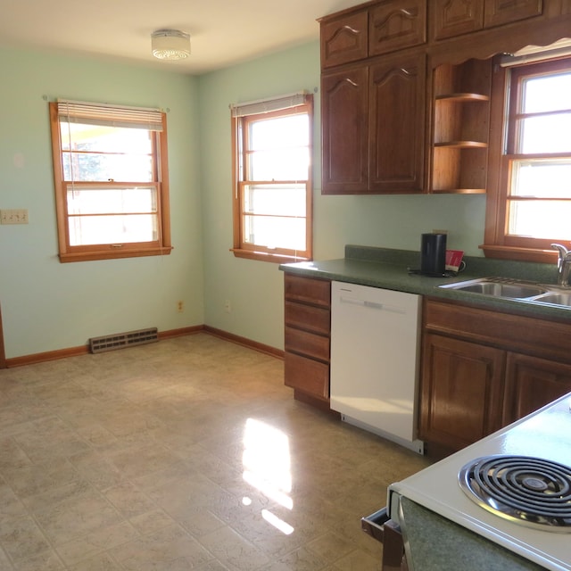 kitchen with white appliances, baseboards, visible vents, a sink, and dark countertops