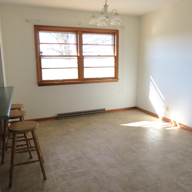 unfurnished dining area featuring a chandelier, a healthy amount of sunlight, light floors, and baseboards