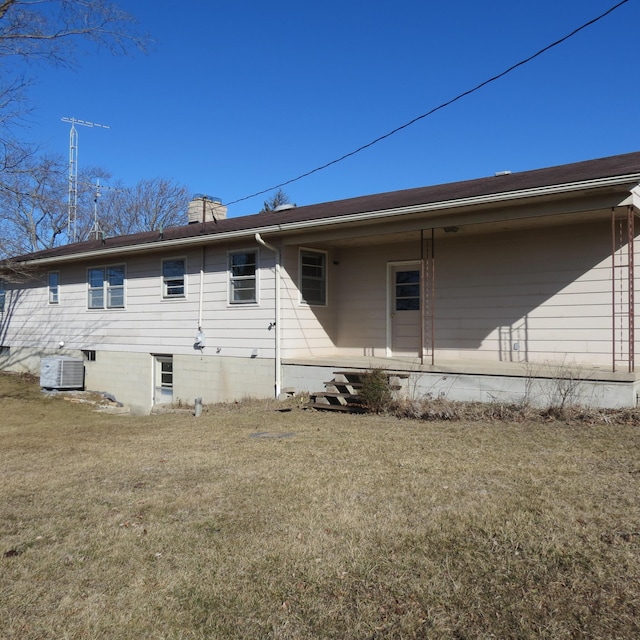 rear view of house featuring a lawn, cooling unit, and a chimney