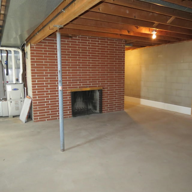 finished basement featuring heating unit, a brick fireplace, and concrete block wall