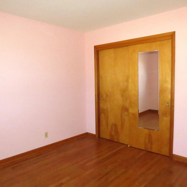 unfurnished bedroom with wood finished floors, a closet, and baseboards