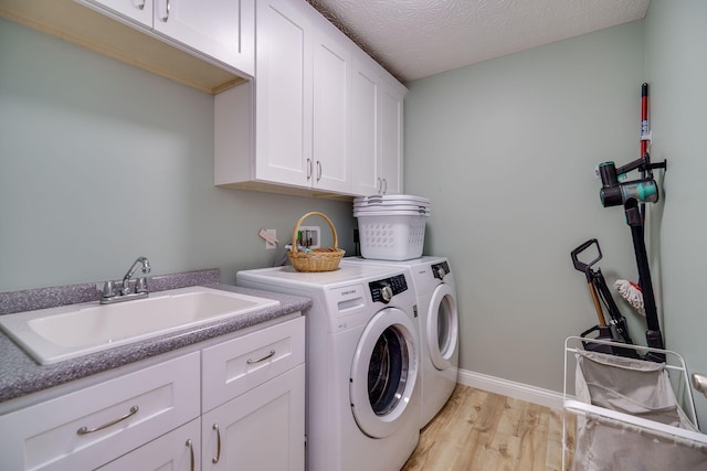laundry area with washer and clothes dryer, a sink, light wood-style floors, baseboards, and cabinet space