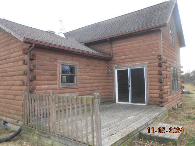 back of house featuring a deck, log exterior, and roof with shingles