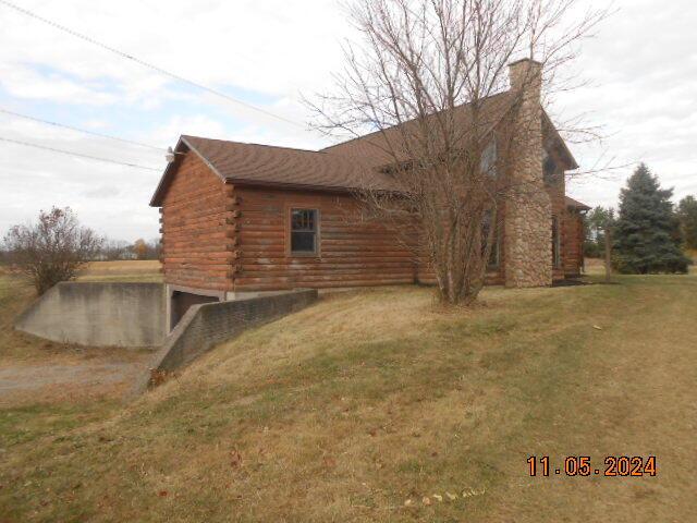 view of property exterior featuring log exterior and a lawn