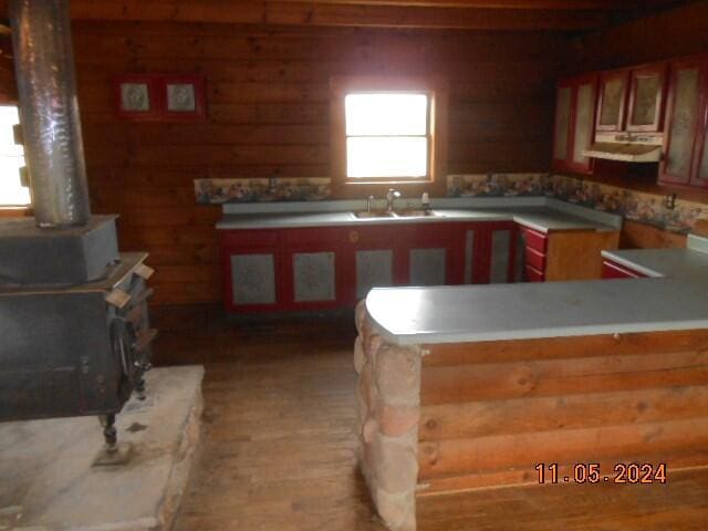 kitchen featuring a peninsula, a wood stove, and a sink