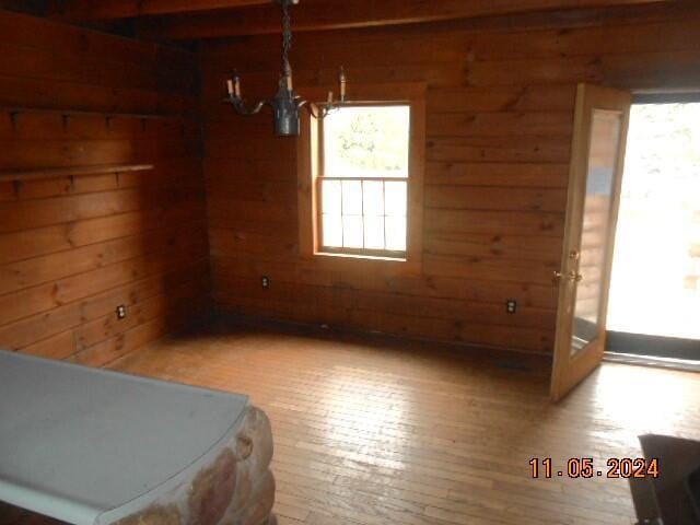 unfurnished dining area with a notable chandelier, wood walls, and wood finished floors