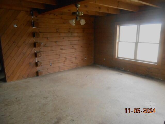 unfurnished room featuring wood walls