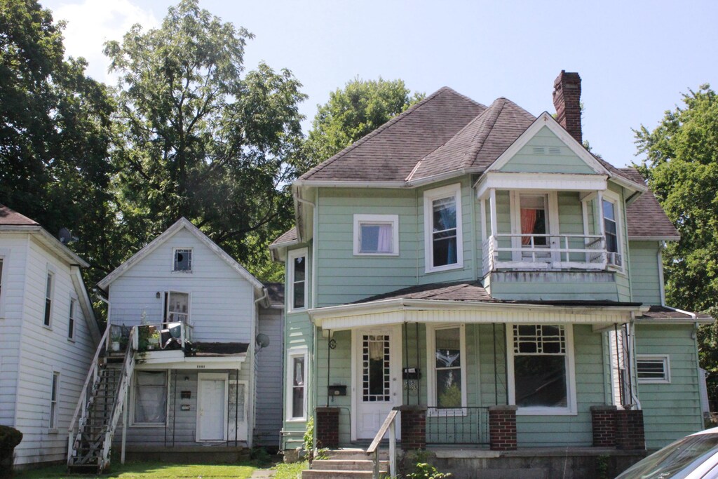 1205 W High St, Springfield, OH 45506 - view of front of home featuring a balcony, a chimney, a porch, stairway, and roof with shingles