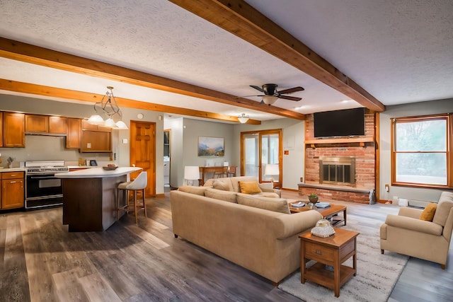 living room featuring ceiling fan, beam ceiling, a fireplace, a textured ceiling, and dark hardwood / wood-style flooring