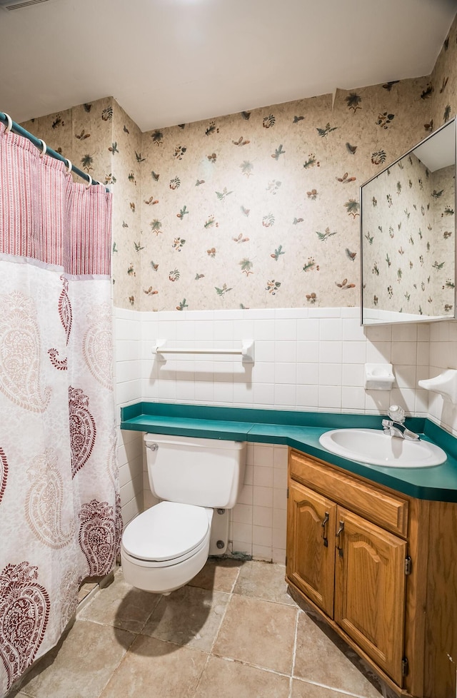 bathroom featuring vanity, tile walls, and toilet