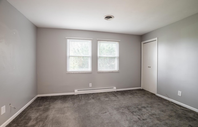 unfurnished room with baseboard heating and dark carpet