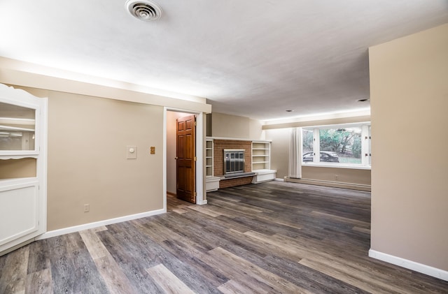 unfurnished living room featuring dark wood-type flooring, a brick fireplace, and a baseboard heating unit