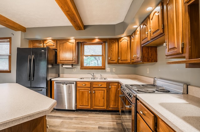 kitchen with stainless steel appliances, sink, beam ceiling, and light wood-type flooring