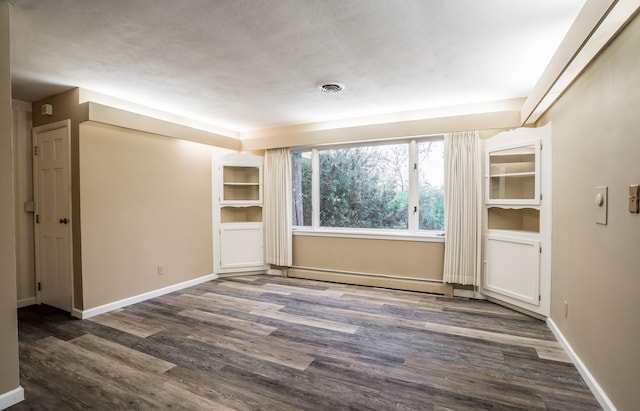 unfurnished room featuring dark wood-type flooring and a baseboard radiator