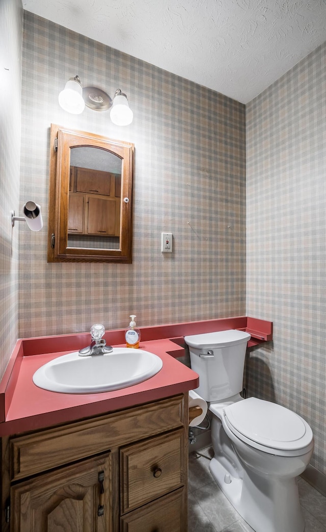 bathroom featuring vanity, a textured ceiling, tile patterned floors, and toilet