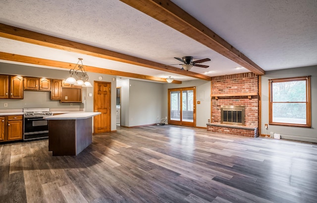 kitchen featuring pendant lighting, stove, a textured ceiling, a kitchen island, and a brick fireplace