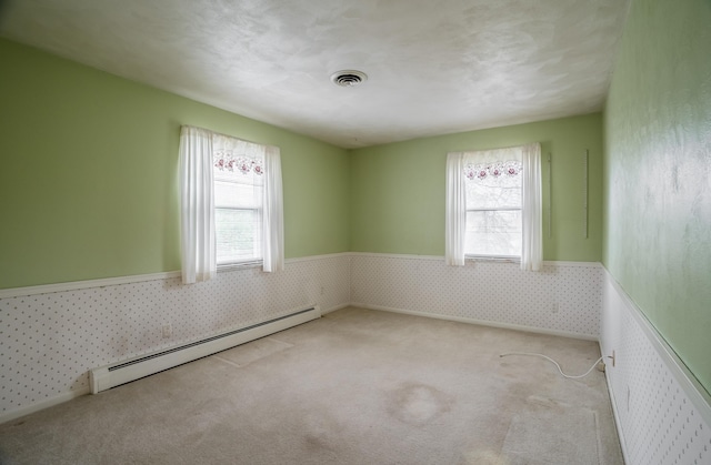 spare room with a healthy amount of sunlight, light carpet, and baseboard heating