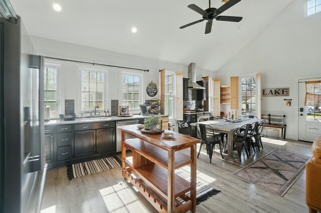 9436 Cottonwood Dr, Huntsville, OH 43324 - kitchen with stainless steel appliances, a sink, high vaulted ceiling, a ceiling fan, and wall chimney exhaust hood