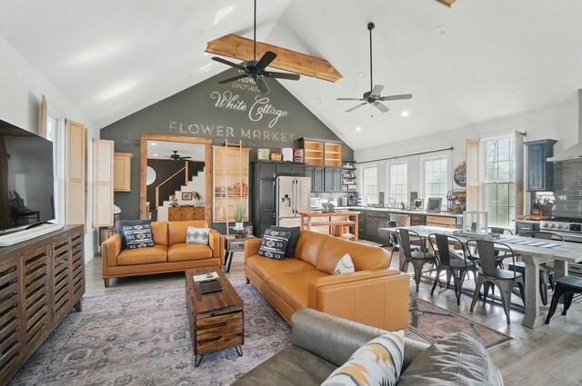 9436 Cottonwood Dr, Huntsville, OH 43324 - living room featuring beam ceiling, high vaulted ceiling, ceiling fan, light wood-type flooring, and stairs