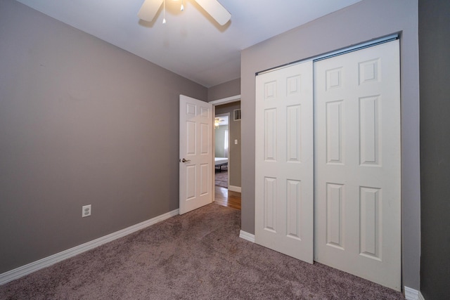 unfurnished bedroom featuring a ceiling fan, baseboards, dark colored carpet, and a closet