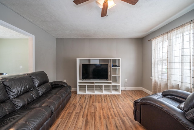 living area with a textured ceiling, wood finished floors, a ceiling fan, and baseboards