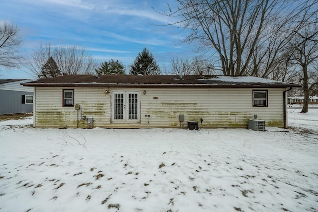 snow covered back of property featuring central AC